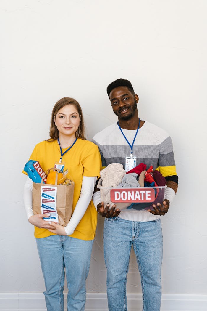 Two volunteers holding donation boxes and smiling, promoting charitable giving.